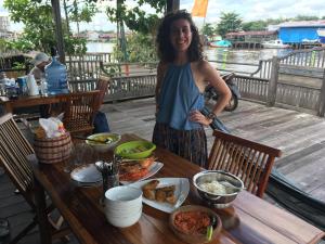 a woman standing in front of a table of food at Arut Riverside Guesthouse in Pangkalan Bun
