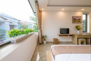 a bedroom with a bed and a window with plants at Hoai River Hoi An Homestay in Hoi An