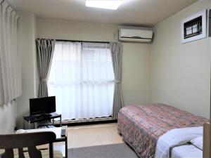 a bedroom with a bed and a window with a television at Business Hotel Century in Nara