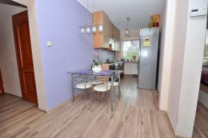 Una cocina con mesa y sillas y un refrigerador. en Pokoje Gościnne AnKaDa, en Władysławowo