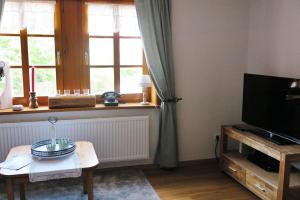 ein Wohnzimmer mit einem TV und einem Tisch in der Unterkunft Fachwerktraum im Hof in Alheim