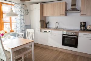 eine Küche mit weißen Schränken, einem Tisch und einem Waschbecken in der Unterkunft Fachwerktraum im Hof in Alheim
