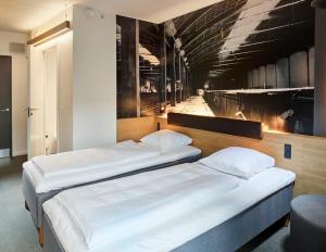 Zleep Hotel Aalborg في ألبورغ: سريرين في غرفة مع لوحة على الحائط