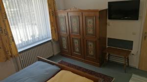 a bedroom with a bed and a tv and a cabinet at Hotel Hecker Braunlage in Braunlage