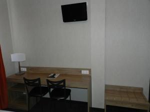 a room with a desk with two chairs and a television on the wall at Hôtel Gloria & Avenue in Lourdes