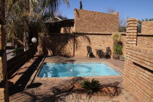 ein kleiner Pool in einem Garten mit zwei Stühlen in der Unterkunft Kuruman Inn in Kuruman