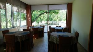 a dining room with tables and chairs and windows at Astron in Loutra Ipatis