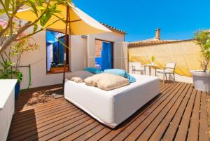 a bed on a deck with an umbrella at Cas Ferrer Nou Hotelet in Alcudia