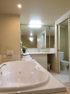 a large bathroom with a tub and a toilet at Madison Spa Motel - Adults Only in Moama