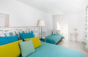 a bedroom with two beds with blue and yellow pillows at Casa Gaia in Capri