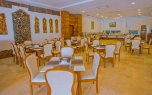 um restaurante com mesas e cadeiras num quarto em Mandalay Lodge Hotel em Mandalay
