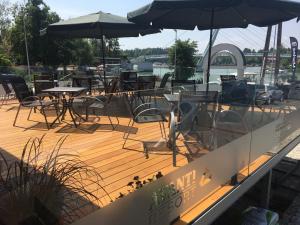 a wooden deck with tables and chairs and umbrellas at Avanti Resort Mikołajki , w centrum przy jeziorze i promenadzie, śniadanie , obiad lub obiadokolacja in Mikołajki