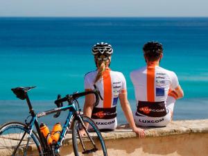 two people sitting on a wall looking at the ocean at Cas Ferrer Nou Hotelet in Alcudia