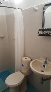 a white bathroom with a toilet and a sink at La Natura Hostel & Pool in Palomino