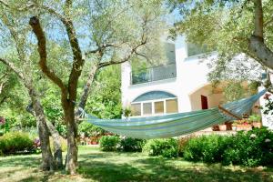 a hammock hanging from a tree in front of a house at Apartment Ponoš in Krk