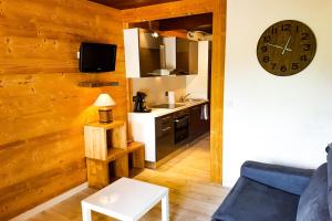 a living room with a blue couch and a clock at Studio Panorama - Vue montagne et village, Centre la Clusaz - AravisTour in La Clusaz