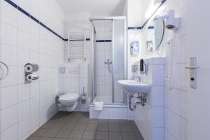 a bathroom with a toilet, sink, and mirror at a&o Frankfurt Galluswarte in Frankfurt