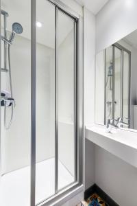 La salle de bains est pourvue d'une douche, d'un lavabo et d'un miroir. dans l'établissement hotelF1 Annecy Argonay, à Argonay