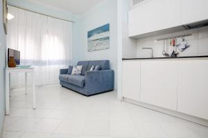 un soggiorno con sedia blu e una cucina di Bilocale il Nido Blu a Santa Teresa di Gallura