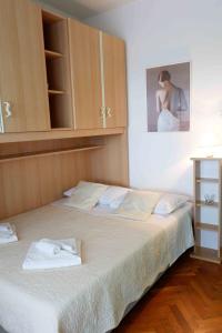 a bedroom with a large bed with a cabinet at Apartment Ponoš in Krk