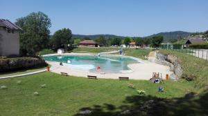 a large swimming pool with people in a park at L'appart de lônes in Hauteville-Lompnes