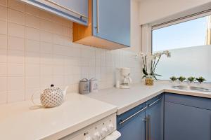 a kitchen with blue cabinets and a vase on the counter at Vlaeberg Cottage in Kortemark