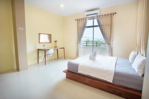a bedroom with a bed and a desk and a window at Aura Residence in Savannakhet