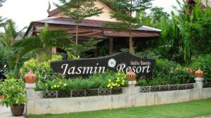 een bord voor een resort met bloemen bij Jasmin Resort - SHA Plus in Khao Lak