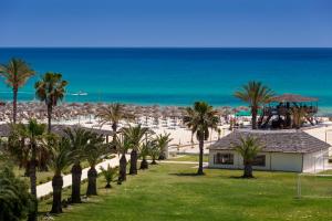 a view of a beach with palm trees and a building at AQI Venus Beach in Hammamet