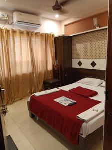sypialnia z łóżkiem z czerwonym kocem w obiekcie hotel sangeeth lodging w mieście Mysuru