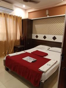 1 dormitorio con 1 cama grande con manta roja en hotel sangeeth lodging, en Mysore