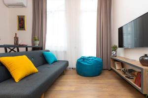 ein Wohnzimmer mit einem blauen Sofa und einem TV in der Unterkunft Wehost Apartment for 3 in Tbilisi City
