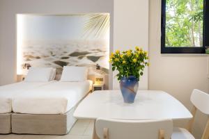 a room with two beds and a vase of flowers on a table at Forum City Apartments in Chania