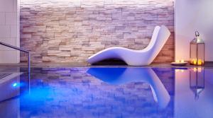 a swimming pool with a white chair sitting next to a brick wall at Auenwald Hotel und Apartmenthaus in Leipzig
