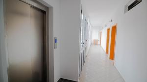 a corridor with white walls and a hallway with doors at Sun N Blue Hotel in Sarandë