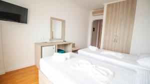 two white beds in a room with a mirror at Sun N Blue Hotel in Sarandë