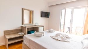 a white bedroom with a bed and a mirror at Sun N Blue Hotel in Sarandë