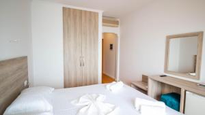 a bedroom with a white bed and a mirror at Sun N Blue Hotel in Sarandë