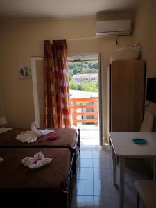 a room with two beds and a door to a balcony at Apartment Alexis Armeno in Marathias