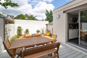 a patio with a wooden table and chairs at Ernestine by Cocoonr in Rennes