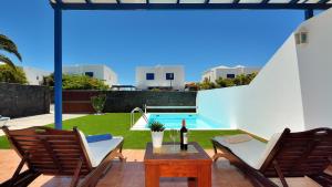 eine Terrasse mit einem Tisch, Stühlen und einem Pool in der Unterkunft Villa Olga in Playa Blanca