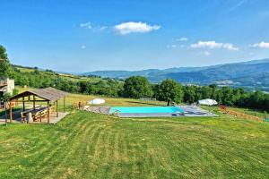a swimming pool in a field with mountains in the background at Casale Daniele by PosarelliVillas in Pratovecchio
