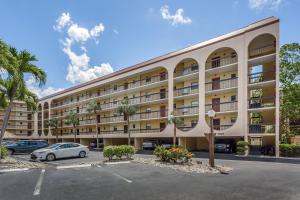 ein großes Apartmenthaus mit einem Auto auf einem Parkplatz in der Unterkunft Anglers Cove in Marco Island