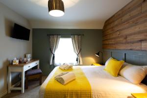 a bedroom with a yellow bed with a wooden headboard at The Poacher Inn in Upton Grey +42 photos