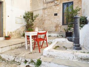 a white table and a red chair on a patio at Dimora di Ponente in Ostuni