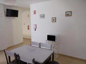 a dining room with a table and a tv on a wall at Casa Amarela by Umbral in Pêra