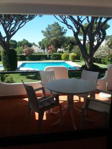 a patio with a table and chairs and a pool at Apartamento Solar dos Pinheiros in Vilamoura +7 photos