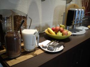 a counter with a bowl of fruit and a glass of milk at Arena Hotel in Henstedt-Ulzburg