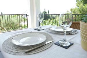 a table with plates and wine glasses on a balcony at Apartment Ponoš in Krk