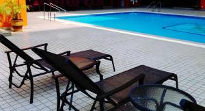 two chairs and a table next to a swimming pool at Hotel Grand Continental Kuantan in Kuantan
